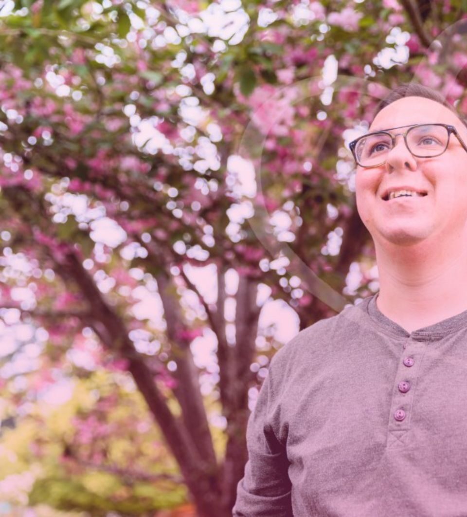 A man smiling under blossom trees