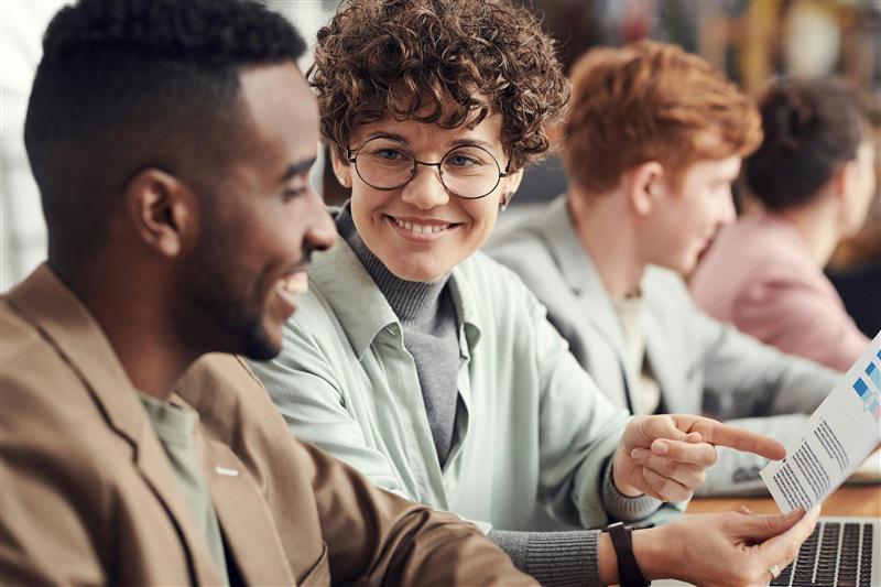 Colleagues smiling together around a laptop